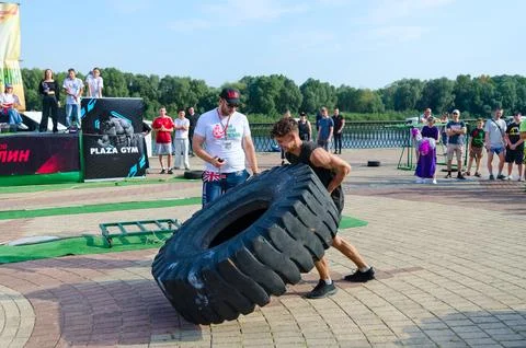 Man performs Exercise Tire Turning during strength competition Stock Photos