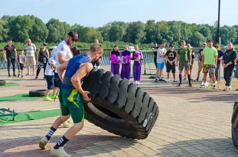 Man performs Exercise Tire Turning during strength competition Foto stock