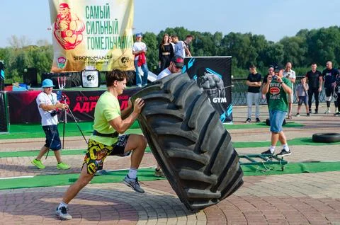 Man performs Exercise Tire Turning during strength competition 스톡 사진