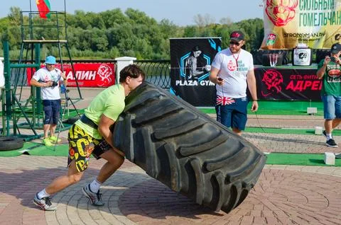 Man performs Exercise Tire Turning during strength competition Stock Photos