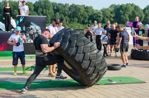 Man performs Exercise Tire Turning during strength competition Stock Photos
