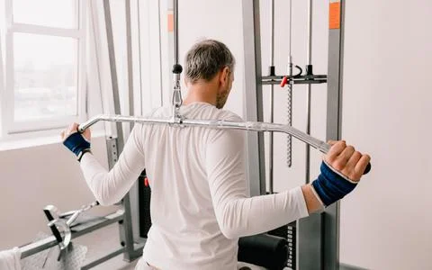A man performs exercises in the gym on a simulator. back training Stock Photos