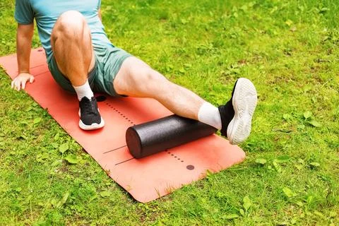 A man performs foam rolling on a mat for myofascial release and post-workou.. Stock Photos