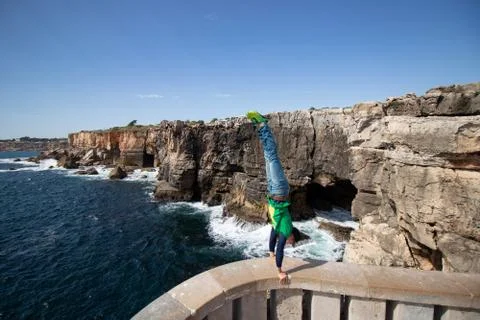 Man performs a handstand on the edge of view point in Portugal. Concept of risk Stock Photos