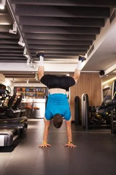 Man performs handstand in gym during daytime workout session Stock Photos