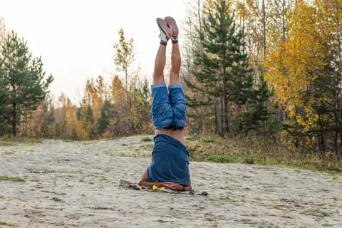 A man performs a headstand exercise. Stock Photos