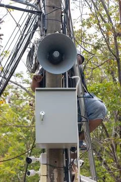 A man performs maintenance on a pole with a megaphone Stock Photos