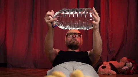 Man performs performs sit-ups using a bottle of water as a weight. Video stock 131584155