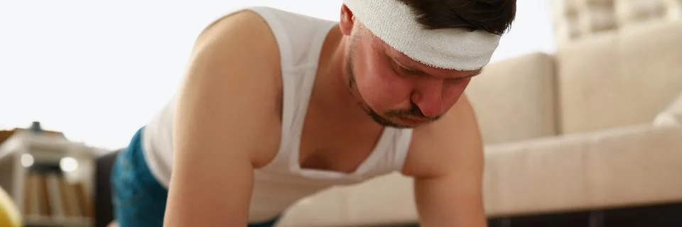 Man performs plank exercises on carpet apartment Stock Photos