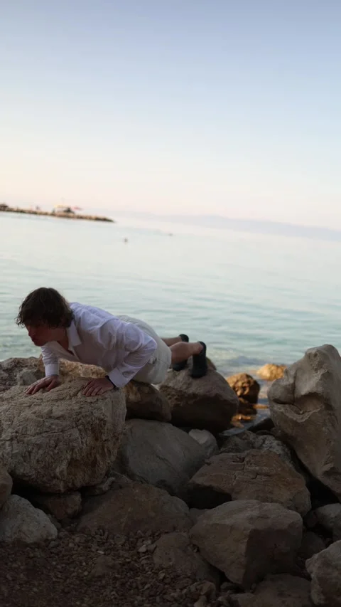 Man performs push ups on seaside rocks during an outdoor vacation workout Vídeo Stock 341621818