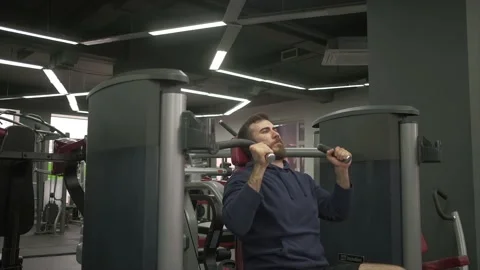 A man performs raising of the hands with a load on the exerciser for endurance. Stock Footage 130330972