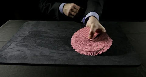 Man performs a ribbon spread on a table then fans the card Stock Footage 100786568