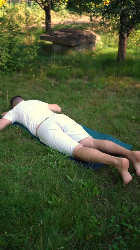 Man performs somatic exercises in the garden in the morning Stock Footage 279248707