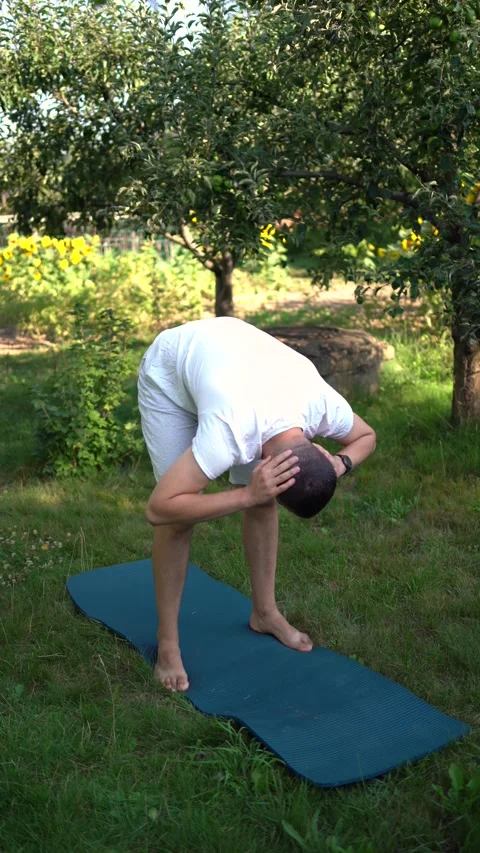 Man performs somatic exercises in the garden in the morning Stock Footage 279248711