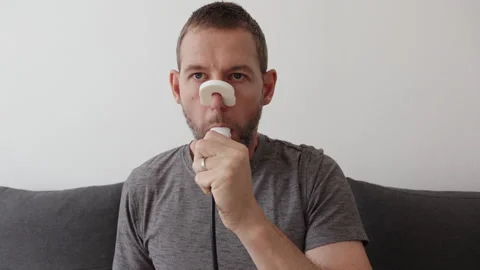 A man performs a spirometry lung test at home using a digital spirometer an.. 動画素材 346720411