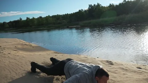 The man performs sport exercises on the shore of the lake Stock Footage 129515176