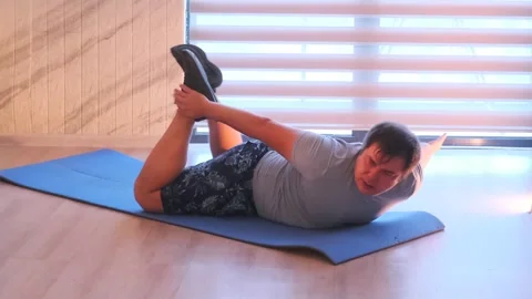 Man performs superman back extension on mat, lifting arms and legs to strengthen Stock Footage 333617948