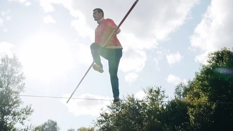 A man performs tricks with a pole standing on a cable above the ground Stock Footage 111539951