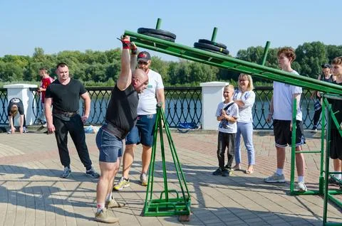 Man performs Viking Press exercise during strength competition Foto stock