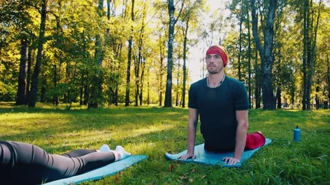 A man performs yoga exercises on a blue mat in the fresh air. Stock Footage 149752392