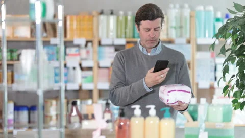 Man in pharmacy scans QR code on sanitary pads product, studies product in Stock Footage 313878882