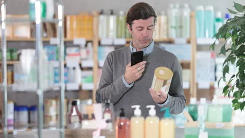 Man in pharmacy scans QR code on infant formula product Stock Footage 320001262