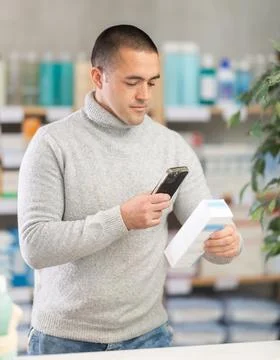 Man in pharmacy scans QR code on emollient for sensitive skin Stock-Fotos