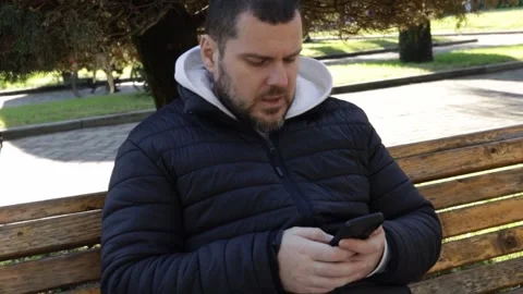 Man with phone in city park, using a mobile device for shopping or banking,.. Stock Footage 300087852