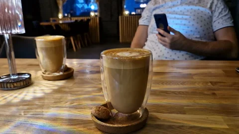 A man with a phone, drinking coffee in a cafe, sending text messages. Stock Footage 245906418