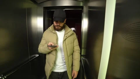 Man with phone enters elevator after opening door and presses button Stock Footage 254970521