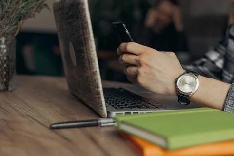 Man with phone in hands using internet while working distantly at table Fotos Stock