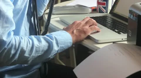 Man on phone using Laptop  with Printer and Union Jack Mug Stock Footage 10908368