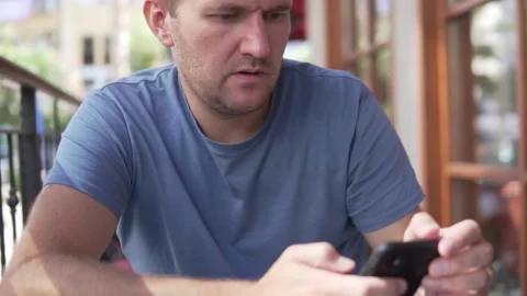 A man with a phone is waiting for his breakfast in the morning in a cafe Stock Footage 209489880