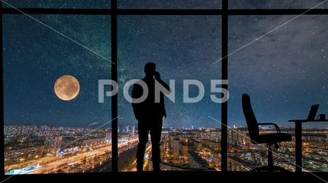 The man phones near the panoramic window on city with starry sky background Stock Photos