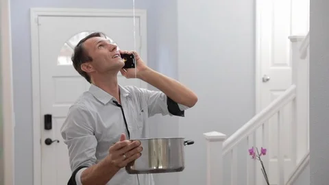 Man Phoning Emergency Plumber After Water Leak At Home Stock Footage 120892819