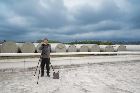 Man photographer standing with camera on tripod outdoors Stock Photos