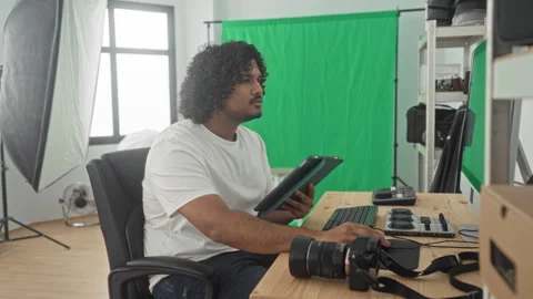 Man photographer taps tablet with hands at desk surrounded by camera and co.. Stock Footage 337396246