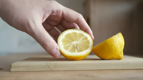 Man pick up a half of lemon in hand from the chopping board close up. Preparing Stock Footage 250609331