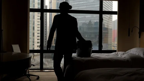 Man pick up suitcase from bed and go away from room, slow motion shot Stock Footage