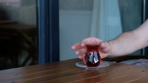 Man Picking Up and Drinking Tea from Glass Cup on Wooden Table Stock Footage 302687029