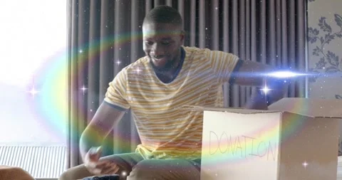 Man picking blue shirt, checking, folding, packing into donation box for 動画素材 321734493