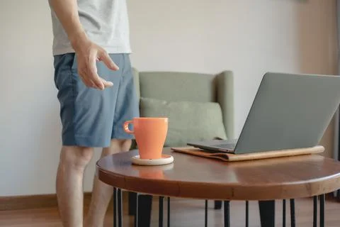 Man is picking up coffee cup while working on his laptop. Stock-Fotos