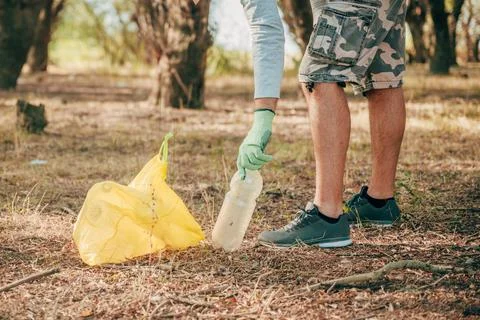 Man picking up discarded plastic from a forest floor during an outdoor clea.. Stock Photos