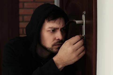 Man picking door lock to break into house. Criminal offence Stock Photos