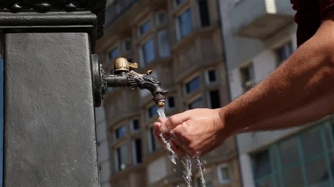 Man is picking up drinking water from old iron tap in street of old city. Stock Footage 95325182