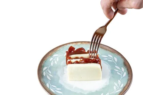 Man picking up with a fork, stacked slices of guava sweet and curd cheese whi Stock Photos