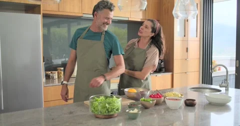 Man picking up green apron prompts partner stepping closer, tying straps, Stock Footage 340965083