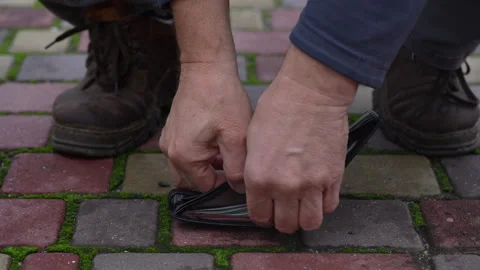 Man picking up lost black wallet full of 100 US dollar banknotes on city street Vidéo 288192161