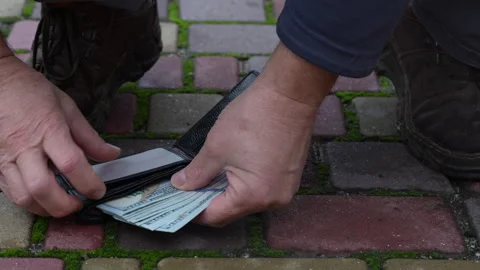 Man picking up lost black wallet full of 100 US dollar banknotes on city street Vidéo 291809022