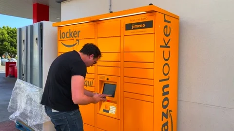 A man picking up a package at the Amazon hub Locker pick up point in Stock Footage 145809359